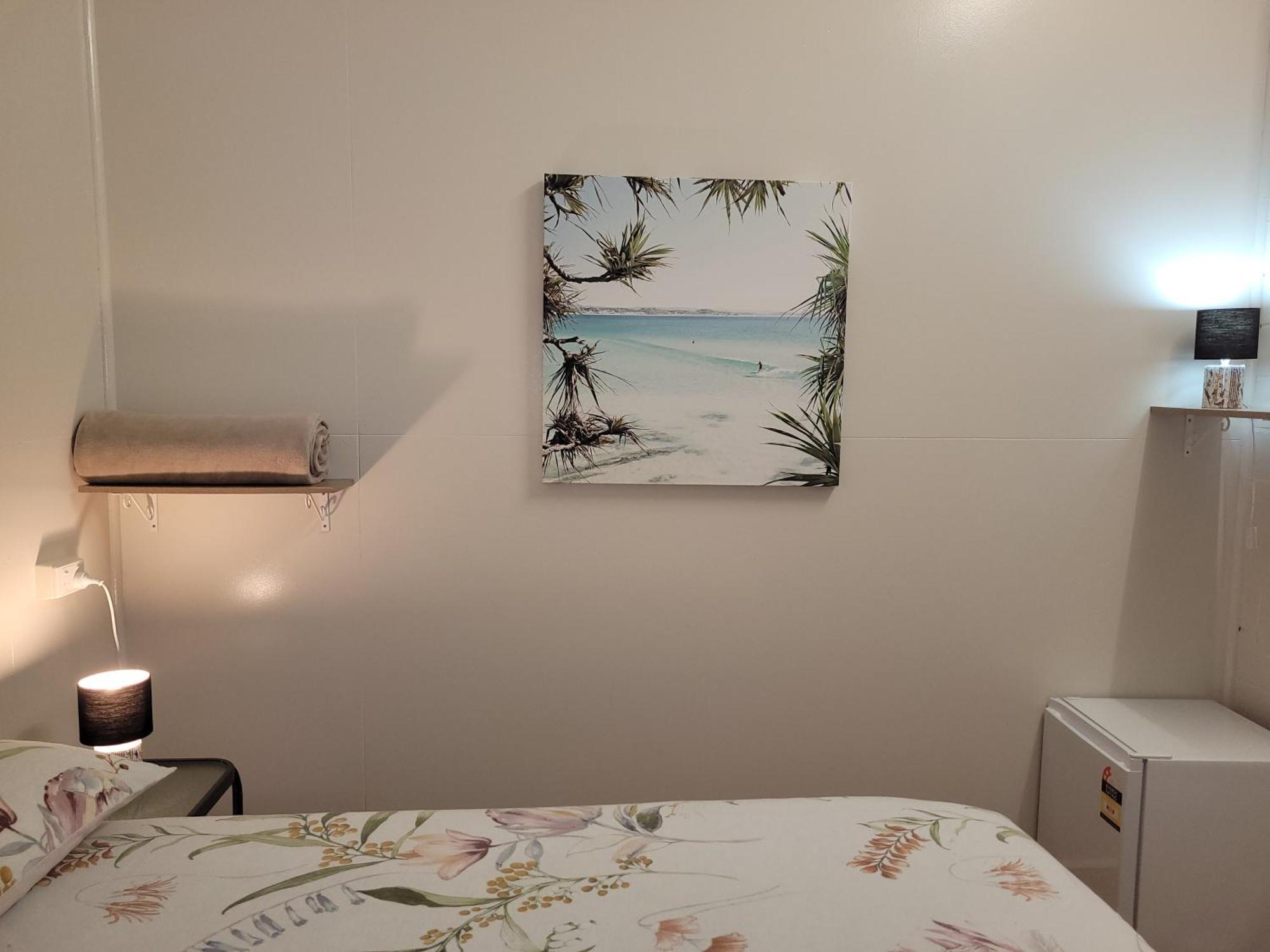 Travellers Paradise Cairns Exterior foto A photograph of a bedroom with a bed, a nightstand, a lamp, a painting, and a television